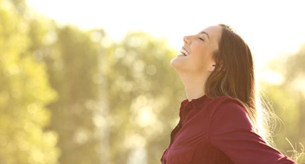 Frau atmet im Sonnenlicht tief durch